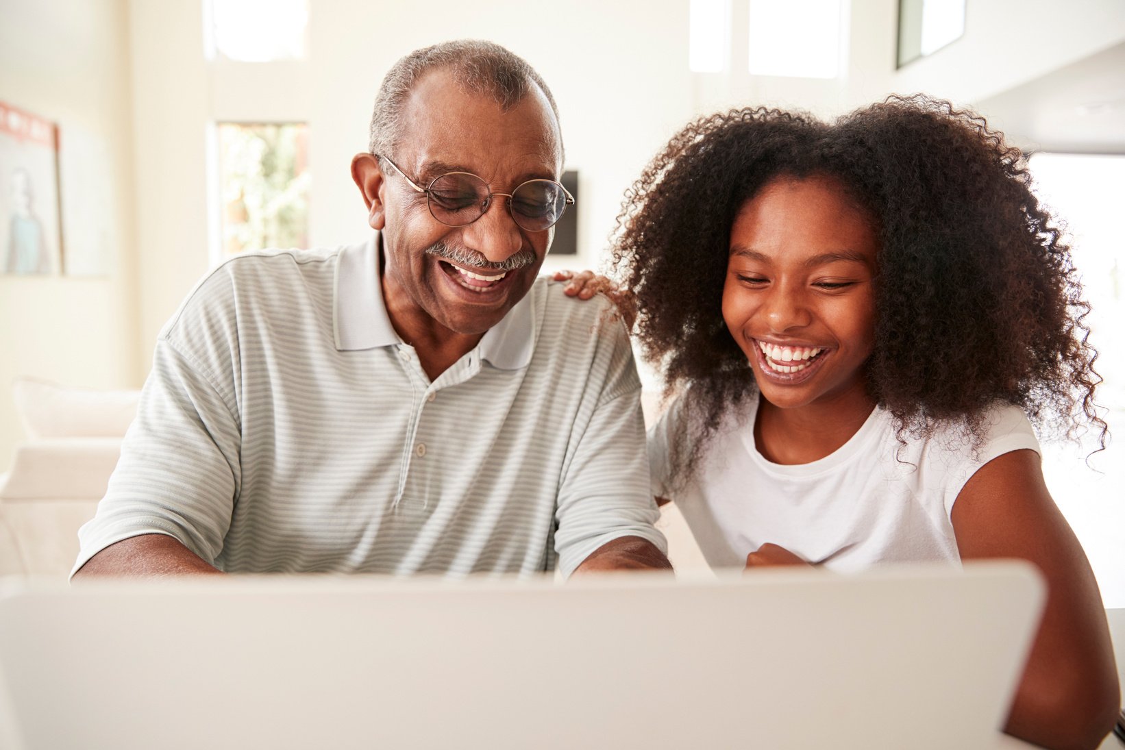 Teenage Black Girl Helping Her Grandfather Use a Laptop Computer